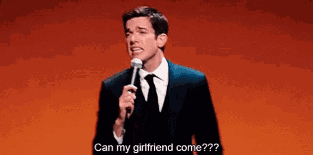 a man in a suit and tie is holding a microphone on a stage and talking into it .