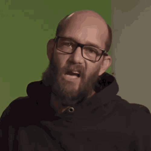 a bald man with a beard wearing glasses and a black hoodie