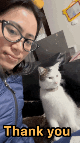 a woman wearing glasses holds a cat in front of a thank you sign