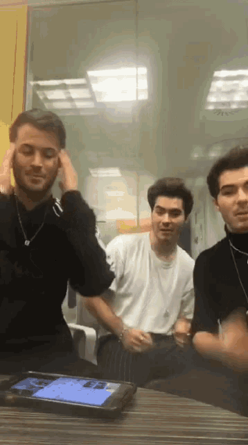 a group of young men are sitting around a table with a phone in front of them