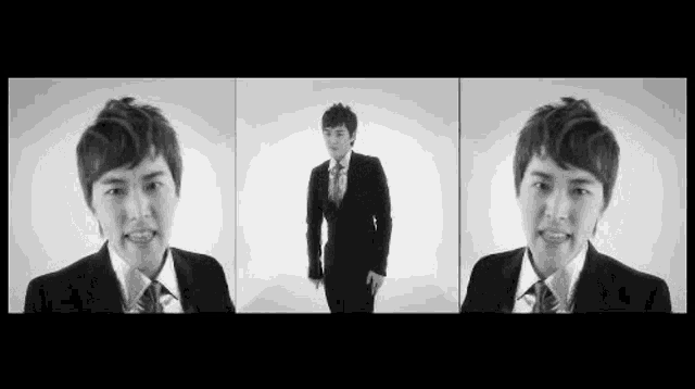 a man in a suit and tie is standing in front of a white wall in a black and white photo .
