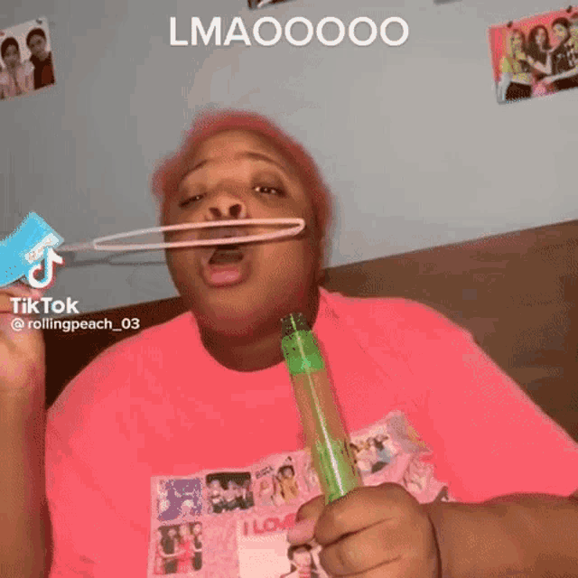 a woman with pink hair is blowing soap bubbles with a toothbrush .