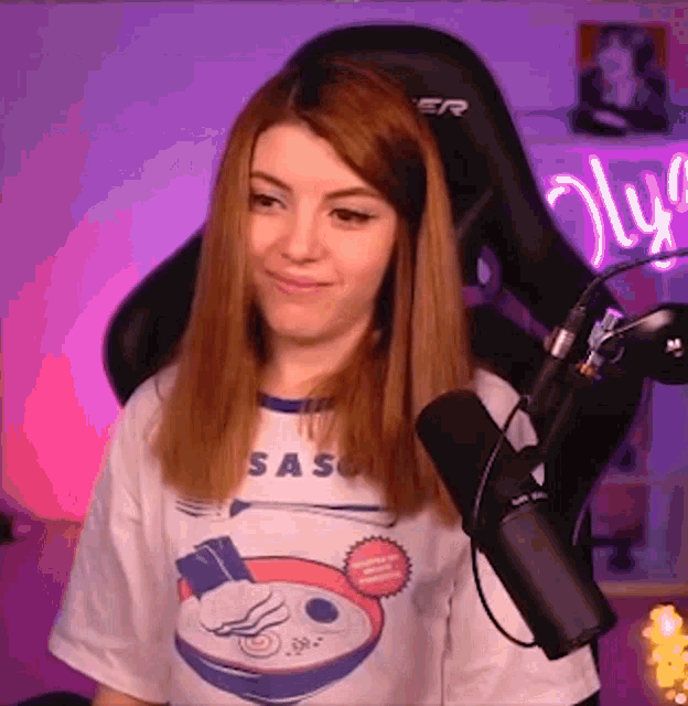 a woman wearing a saso t-shirt stands in front of a microphone
