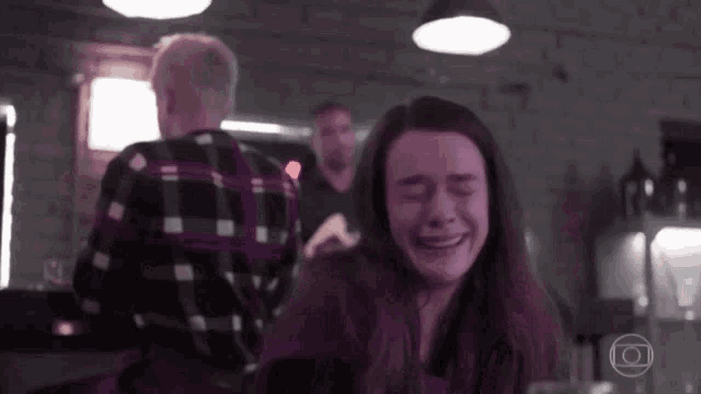 a woman is crying in front of a man in a plaid shirt in a dark room .