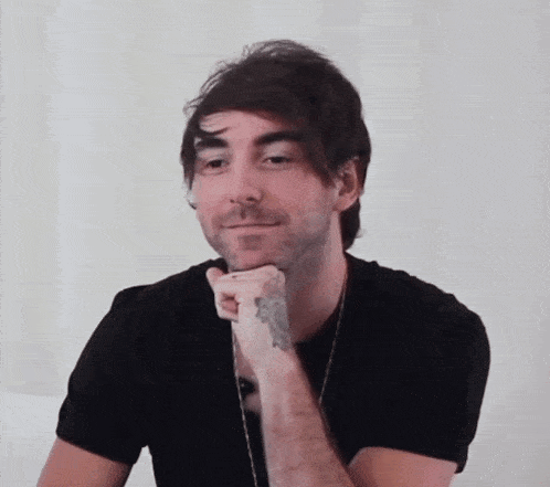 a man with a tattoo on his arm is wearing a black shirt and smiling .