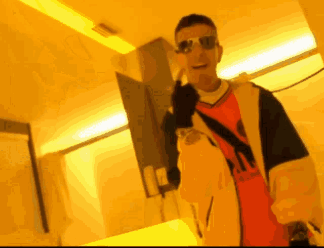 a man wearing sunglasses and a red adidas shirt