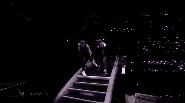 a couple of men are standing on top of a bridge holding hands .
