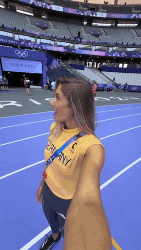 a woman wearing a yellow shirt that says germany stands on a track