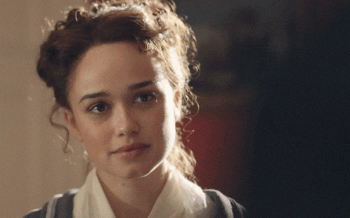 a woman with curly hair looks at the camera with a serious look on her face