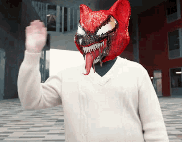 a man in a white sweater has a red cat mask on his face