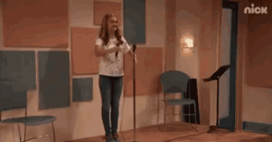 a woman is singing into a microphone in a room with korean writing .