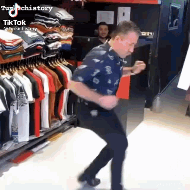 a man is dancing in front of a rack of shirts in a store .