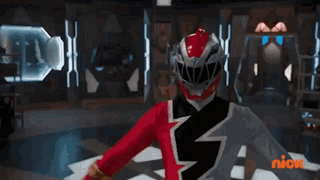 a red power ranger is standing in a room with a red light coming out of his chest .