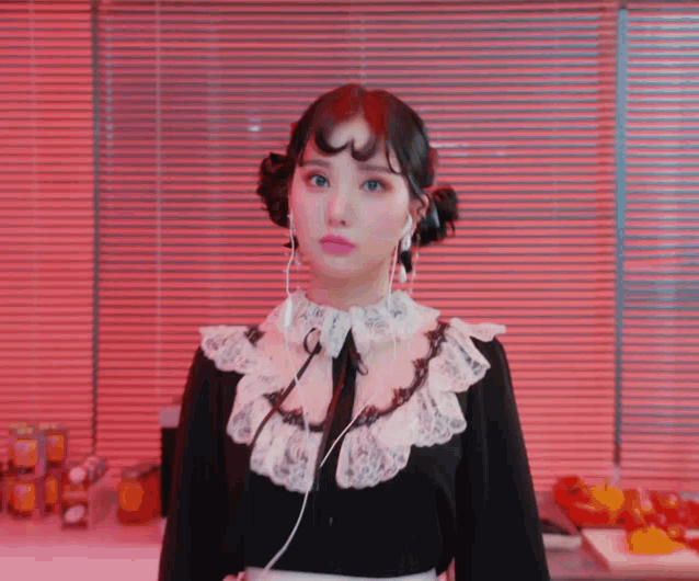 a woman wearing a black and white dress and ear buds is standing in front of a window .