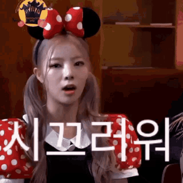 a woman wearing a minnie mouse headband and polka dot sleeves is making a funny face .