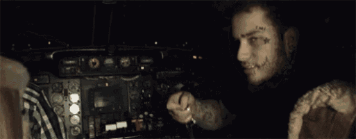 a man with a tattoo on his face pointing at the camera