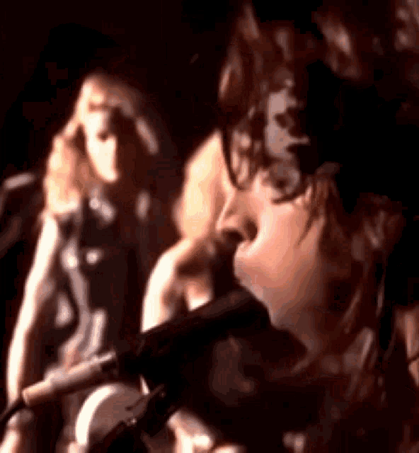 a woman is singing into a microphone while a man stands behind her .