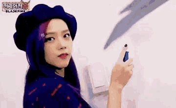 a woman with purple hair and a beret is holding a pair of scissors in her hand .
