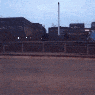 a blurry picture of a street with a fence in the foreground