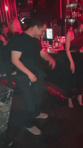 a man in a black shirt is dancing in a bar with a sign that says crac on it