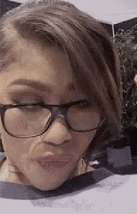 the woman is wearing glasses and making a funny face .