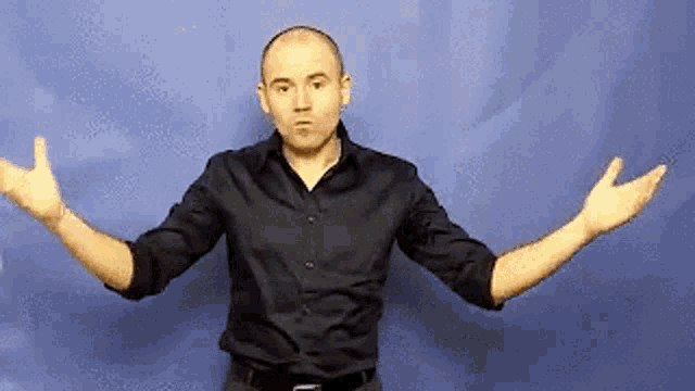 a bald man in a black shirt is standing with his arms outstretched .