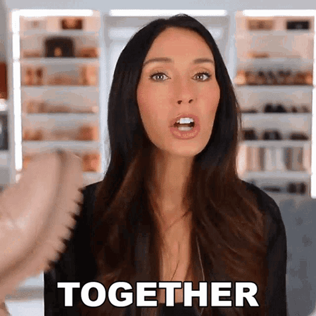 a woman with long dark hair says together in a video
