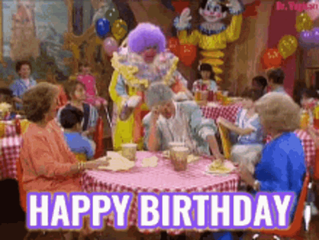 a group of people are sitting around a table with a clown in a purple wig and the words happy birthday on the bottom