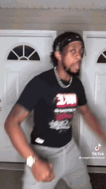 a man wearing a 3m shirt is dancing in front of a white door .