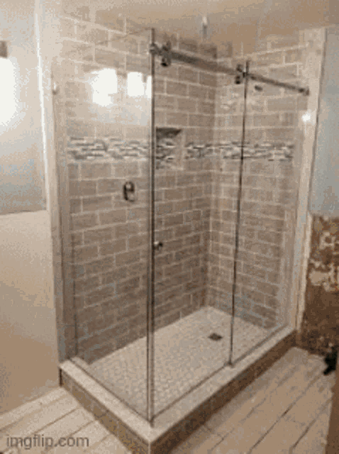 a bathroom with a sliding glass shower door and a brick wall