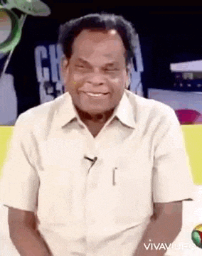 a man in a white shirt is smiling and sitting on a chair .