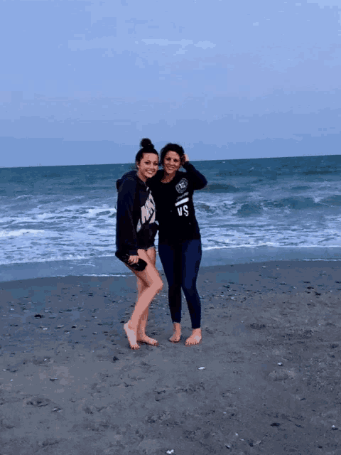 two women standing on a beach with one wearing a shirt that says vs.
