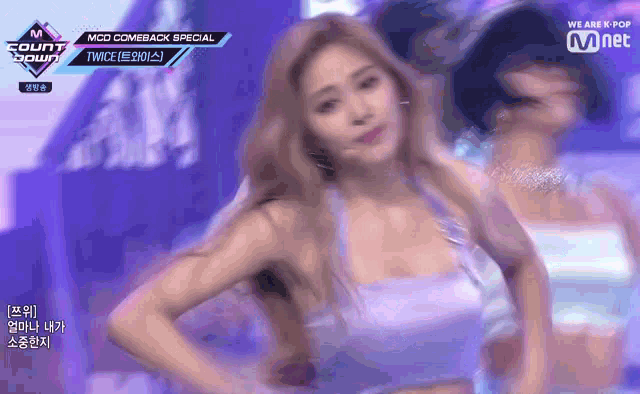 a woman in a purple top is dancing on a stage in front of a mnet logo .