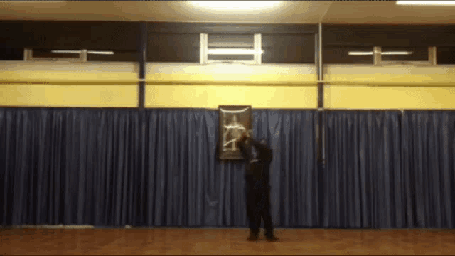 a man is standing in front of a blue curtain in a gym
