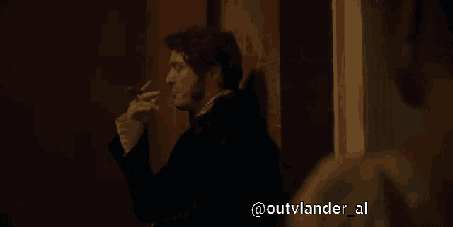 a man is smoking a cigarette with the hashtag outvlander_al