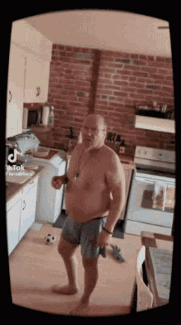 a shirtless man is standing in a kitchen with a brick wall