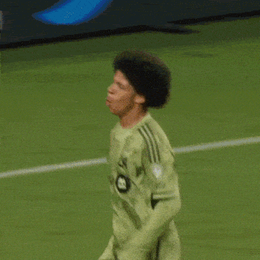 a soccer player wearing a green adidas jersey is running on the field .