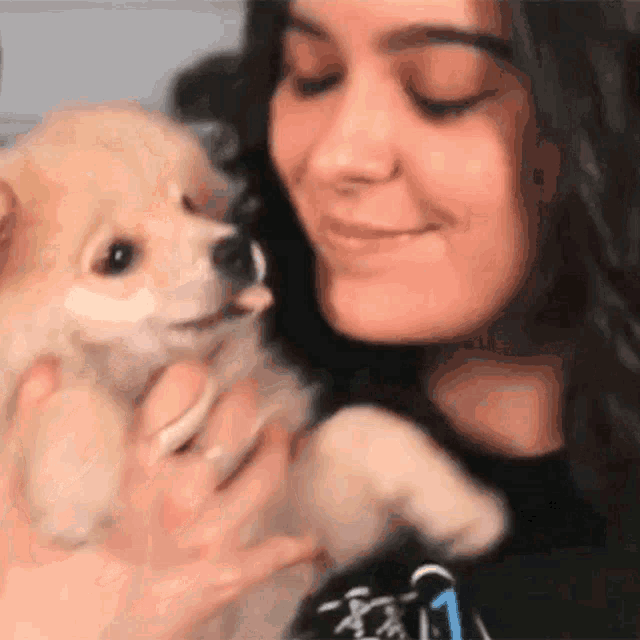 a woman is holding a small dog in her arms