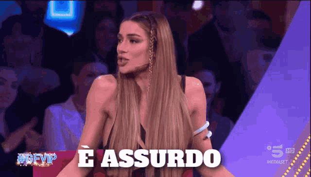 a woman stands in front of a sign that says e assurdo on it
