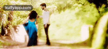 a man is carrying a woman in a blue dress on his shoulders in a forest .