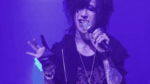 a man is singing into a microphone on a stage with a purple background .