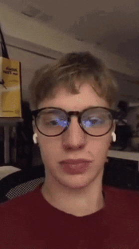 a young man wearing glasses and ear buds is looking at the camera