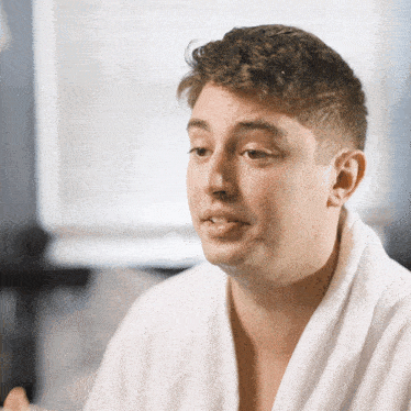 a man in a white robe looks to his left
