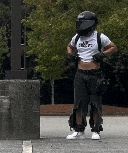 a man wearing a helmet and a crop top that says groovy