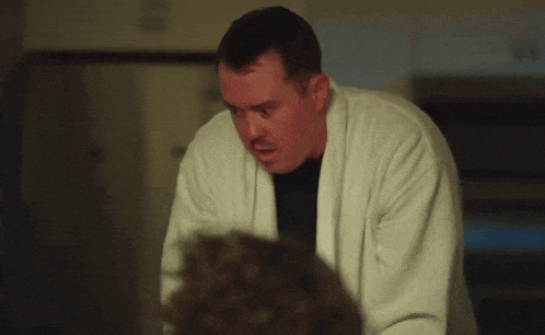 a man in a white robe looks at the camera with a surprised look on his face