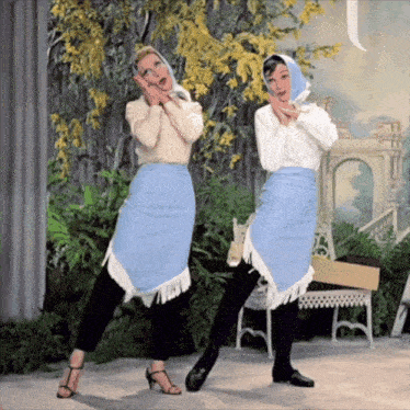 two women wearing blue and white skirts are dancing together