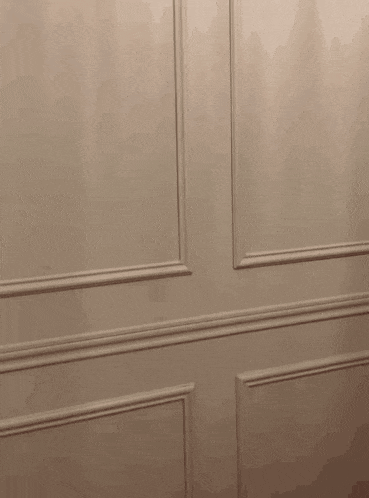 a shadow of a person is cast on a white wall with trim