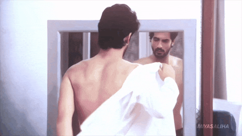 a shirtless man is looking at himself in a mirror with the words miyasaliha on the bottom