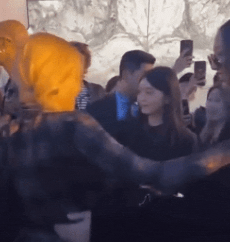 a group of people are standing in a room and taking pictures with their cell phones .
