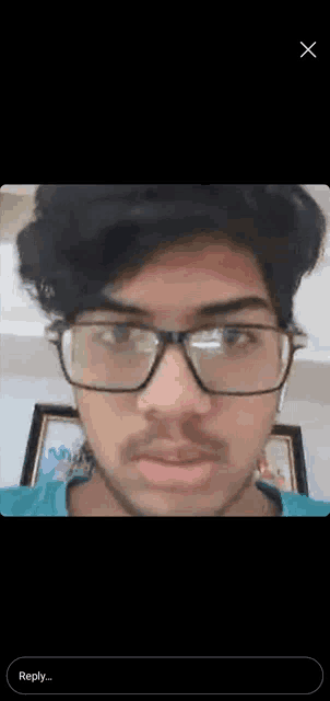 a young man with glasses and a beard is looking at the camera .